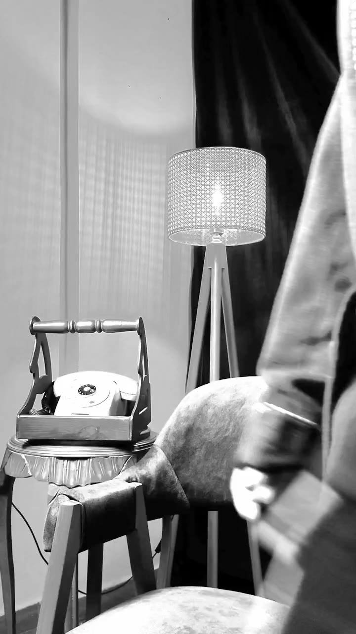 A black-and-white studio corner with a wooden chair and a floor lamp